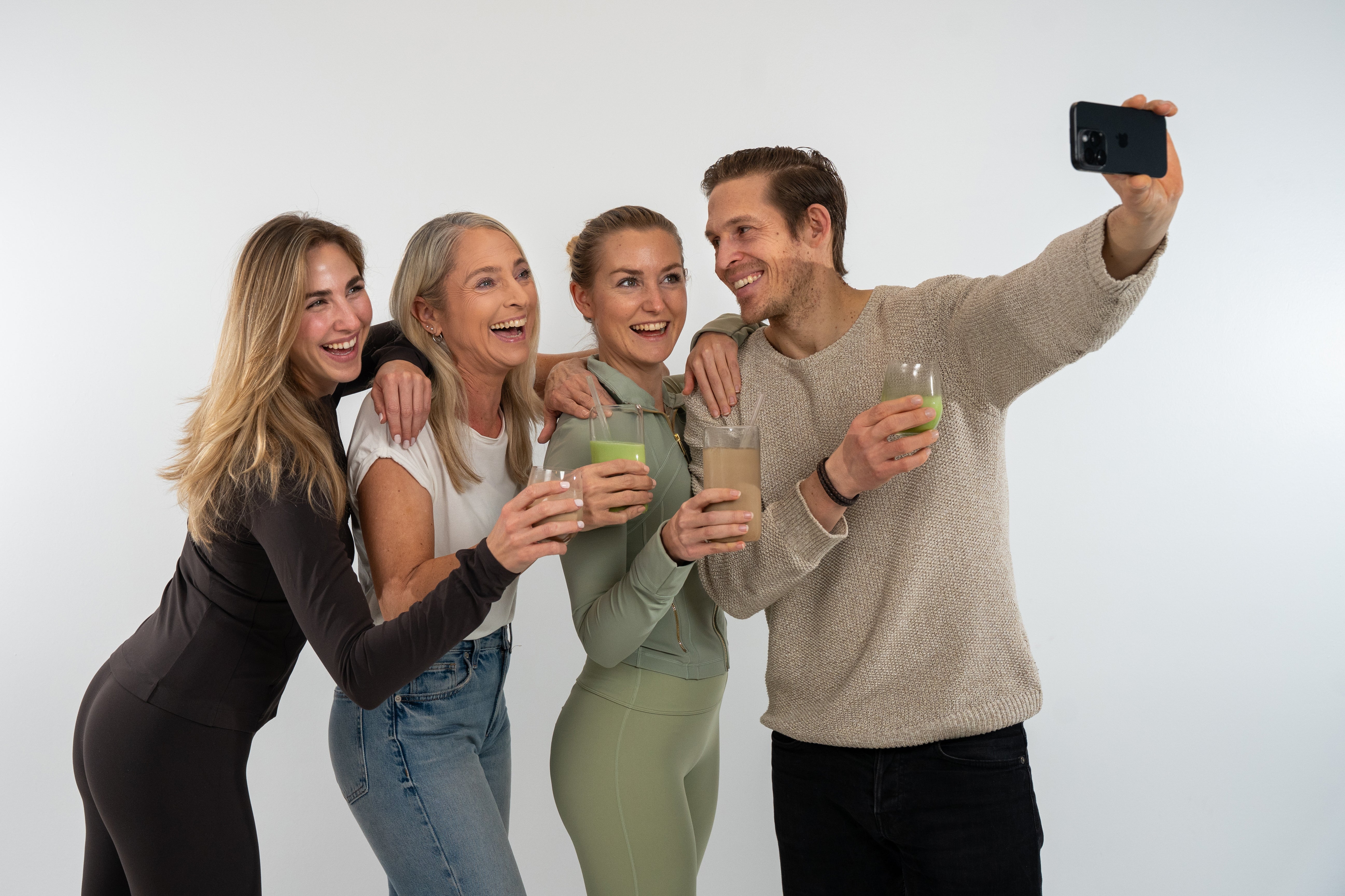 Vier Personen beim Anstoßen mit Smoothies